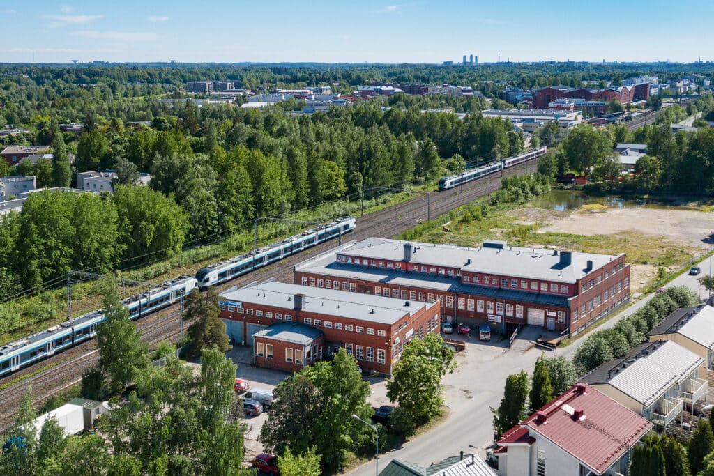 Kiinteistö kuvattuna ilmasta, vasemmalla junaraiteet ja metsikköä.